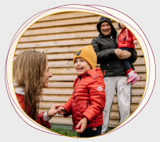 Mutter und Vater mit zwei Kleinkindern draußen, lachend