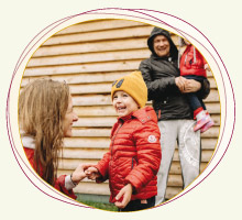 Mutter und Vater mit zwei Kleinkindern draußen, lachend